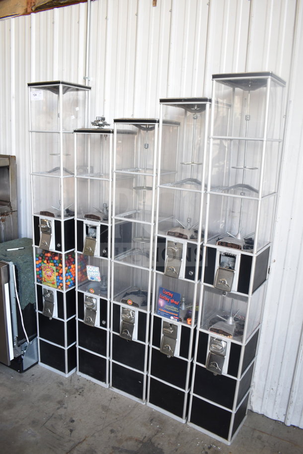 Five double stack vending machines, black and clear acrylic, various sizes, coin-operated, containing candy and snacks.