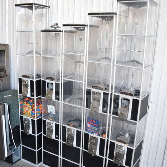 Five double stack vending machines, black and clear acrylic, various sizes, coin-operated, containing candy and snacks.