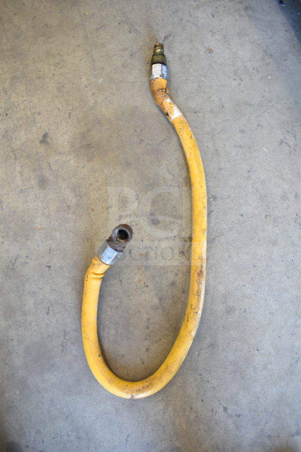 Yellow gas hose with metal connectors; signs of wear; suitable for commercial equipment installation.