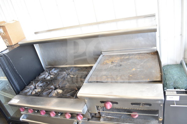 American Range commercial gas 6-burner range with flat top griddle, twin ovens, overshelf, and backsplash on casters.
