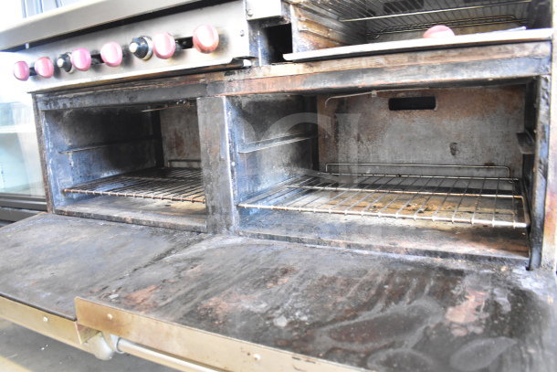 American Range commercial gas-powered 6 burner range with flat top griddle, 2 ovens, overshelf, backsplash, on casters, used condition.