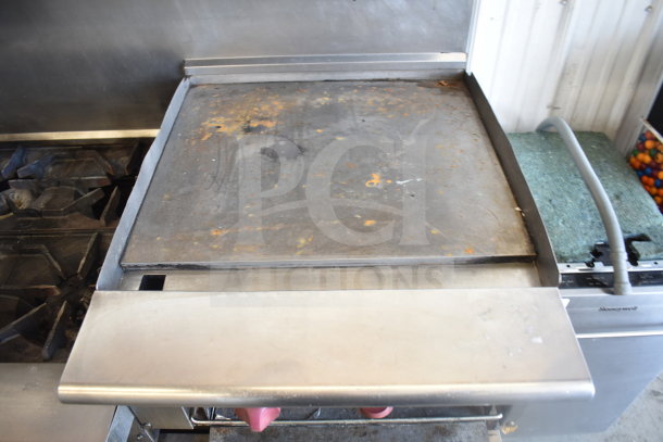 American Range gas-powered 6 burner range with flat top griddle, 2 ovens, over shelf, backsplash, on commercial casters.