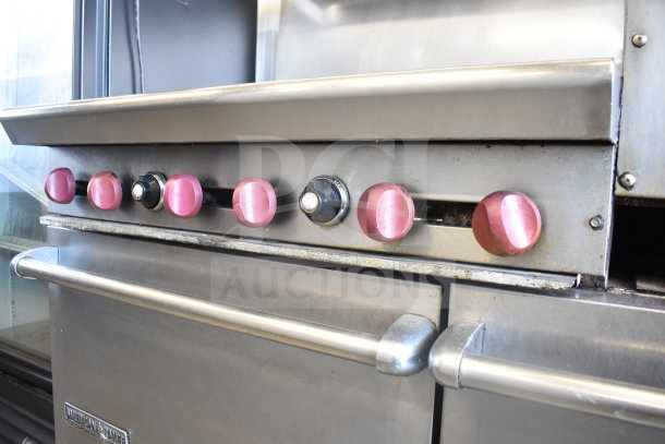 American Range commercial gas stove with 6 pink control knobs, flat top griddle, 2 ovens, over shelf, and backsplash on casters.