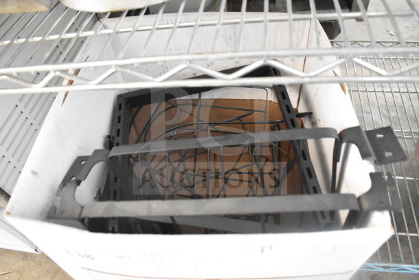 Lot of various metal racks and components in a cardboard box on a wire shelf, suitable for storage or organization.