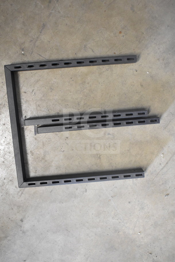 Metal rack sections with slotted holes on a concrete floor, included in a lot of various items.