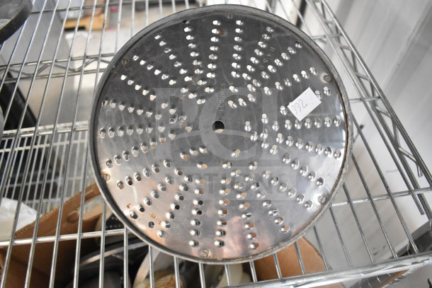 Metal food processor blade with perforations, marked "LEGUMES" and label "992," on a metal rack. Auction of 20 items.