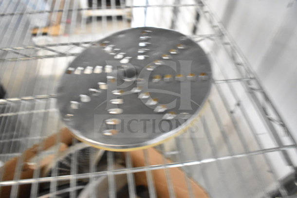 Blurred image of a round metal food processor blade on a wire shelf; part of a lot of 20 various items.