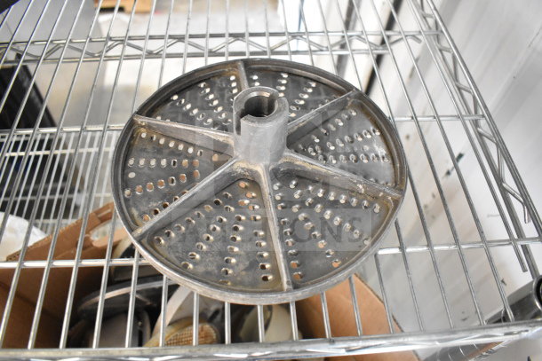 Food processor blade on metal rack, circular with perforations, used condition. Part of 20-item auction lot.
