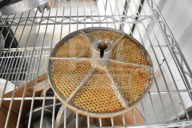 20 food processor blades featuring various designs, metal construction, some with visible rust. Stored on a metal shelf.