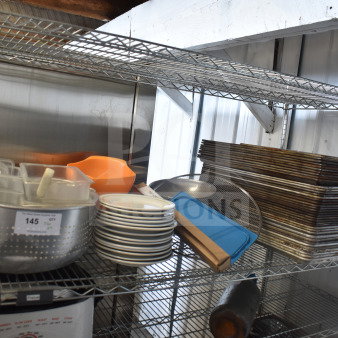 Tiered lot including metal colander, stack of plates, baking pans. Visible tag: "145 QTY." Various kitchen essentials.