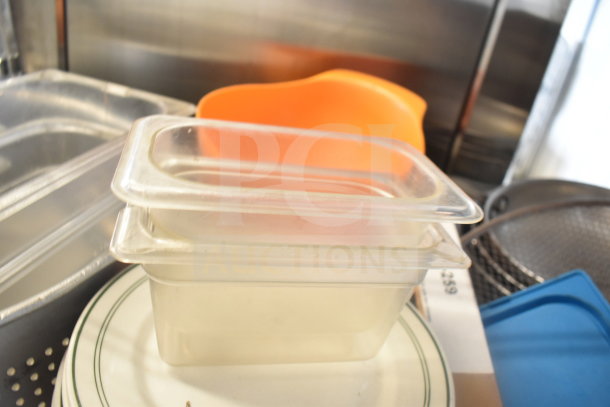 Tiered lot including clear plastic containers, an orange colander, plates with green trim, and baking pans.