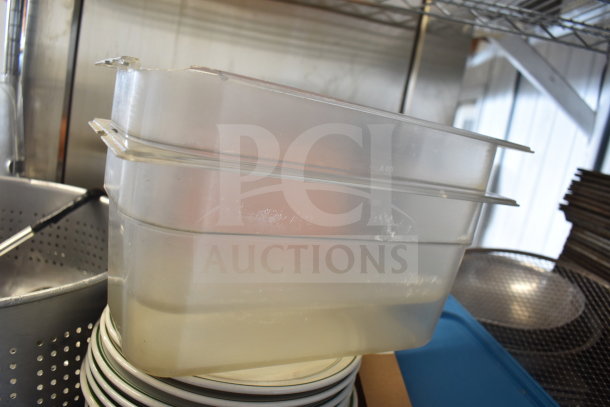 Tier lot including a colander, stacked plates, and clear plastic baking pans, used condition, visible minor wear.