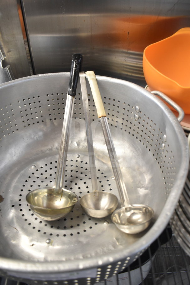 Tier lot featuring a large metal colander with three ladles inside; visible rust, signs of use.