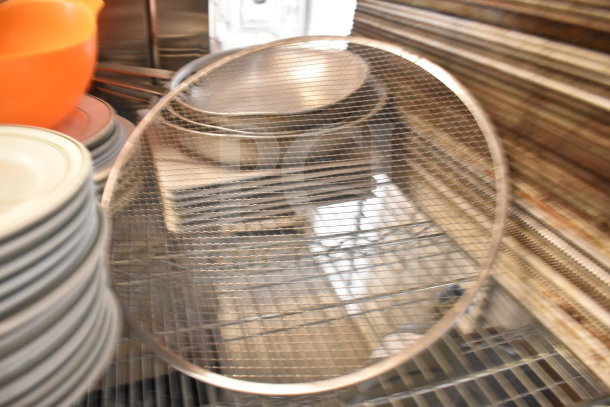Tiered lot including metal colander, stack of white plates, orange bowls, and baking pans, in used condition.
