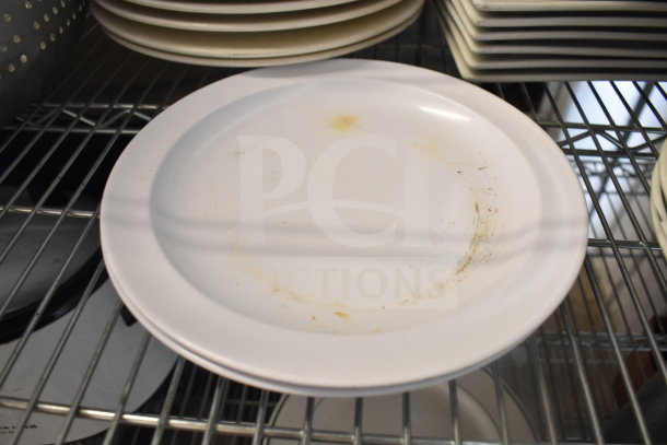 Tiered lot with various kitchen items including a stainless steel colander, stack of white plates showing wear, and baking pans.