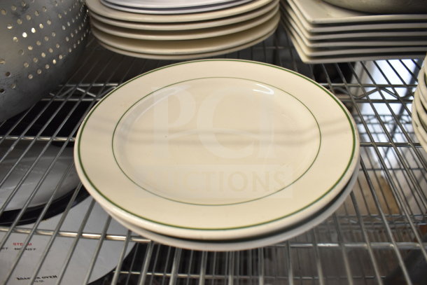Assorted kitchen items including a colander, stacked plates with green trim, and baking pans on a metal rack.