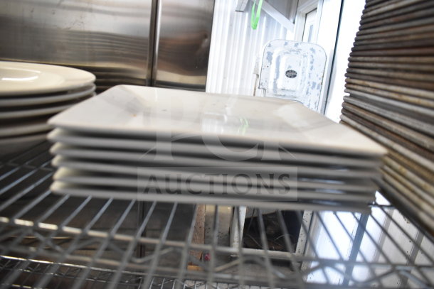 Stack of white square plates on metal shelf, part of tier lot with colander and baking pans, in used condition.