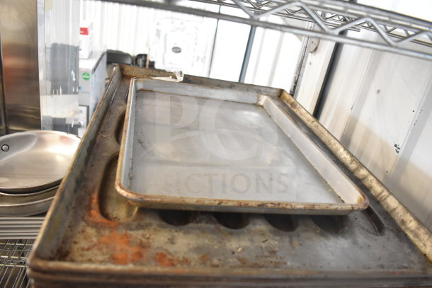 Tiered lot of kitchen items including colander, stack of metal plates, and various baking pans, used condition.