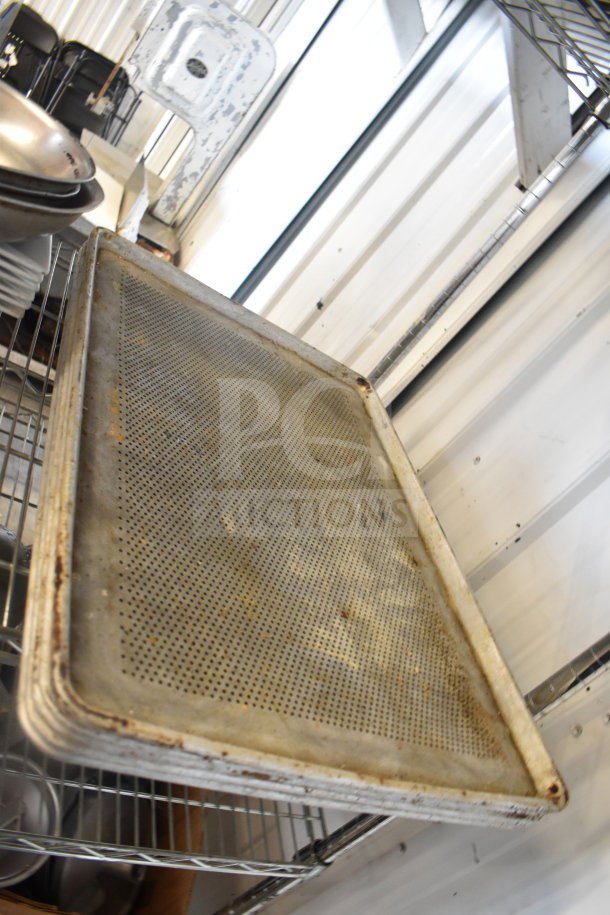 Tiered auction lot with metal colander, plates, and perforated baking pans on a wire rack. Used condition.