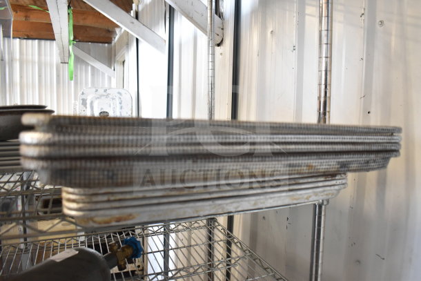 Tiered lot of used colander, plates, and baking pans on metal shelving. Various sizes and conditions.