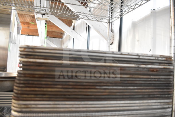 Stacked baking pans on metal shelving; part of a tier lot including colander and plates. Used condition with visible wear.