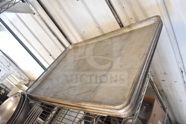 Auction lot featuring a perforated baking pan, stack of plates, and metal colander, all made of stainless steel.
