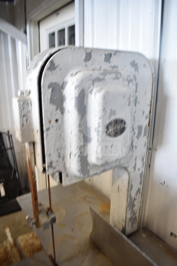 Hobart commercial floor style meat saw with visible wear and chipping paint. Hobart logo on the head.