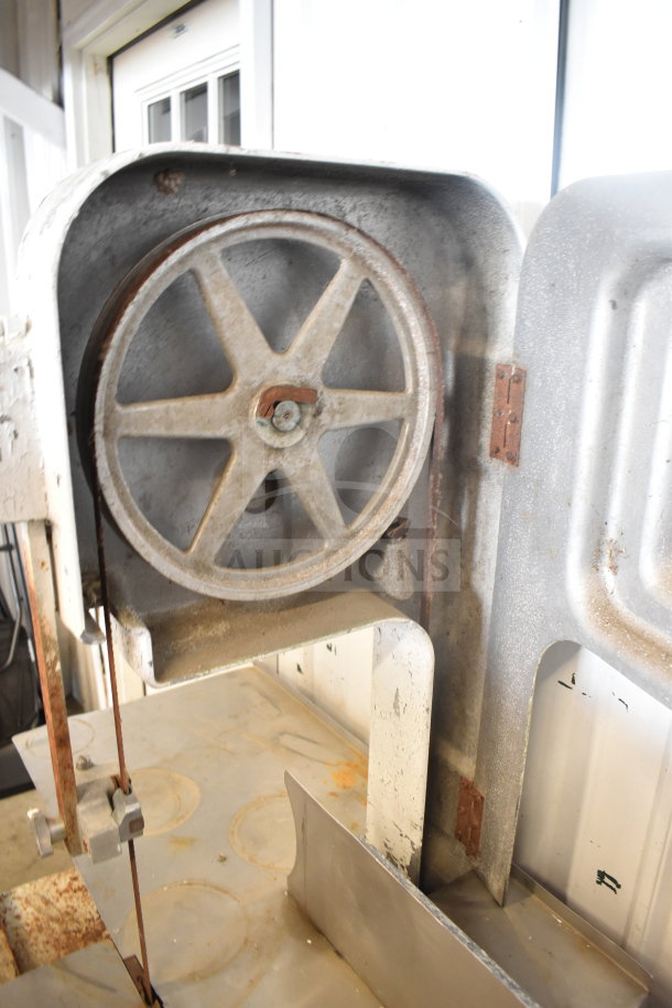 Hobart commercial floor-style meat saw with rust and wear visible, showcasing the blade and wheel mechanism.