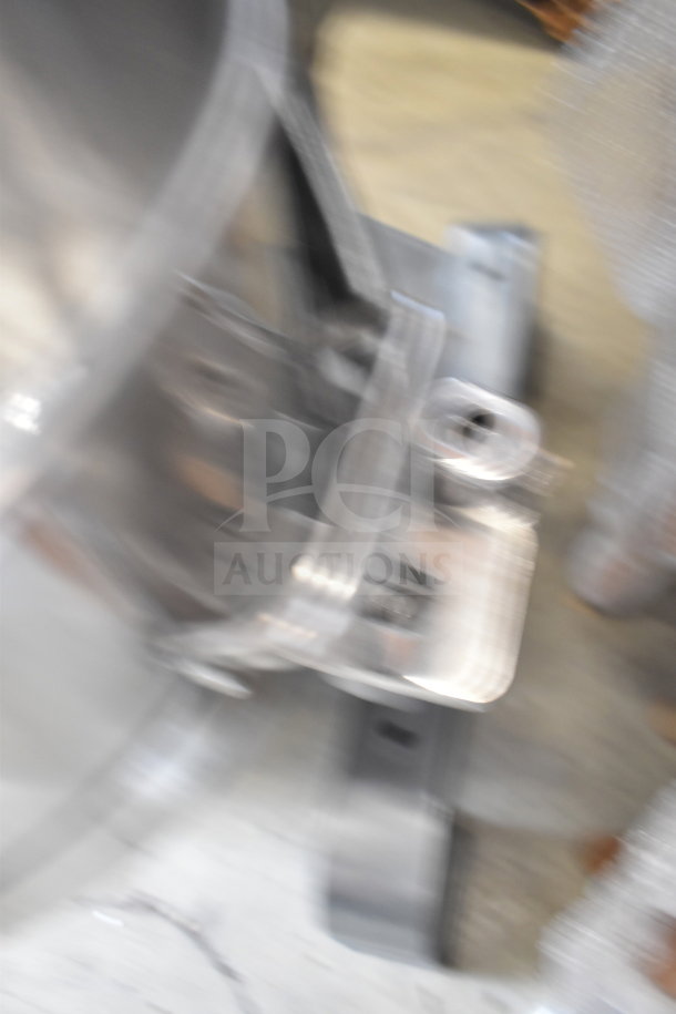 Blurry image of a commercial dough mixer, model MX30H by Avantco, showing parts of the stainless steel structure.