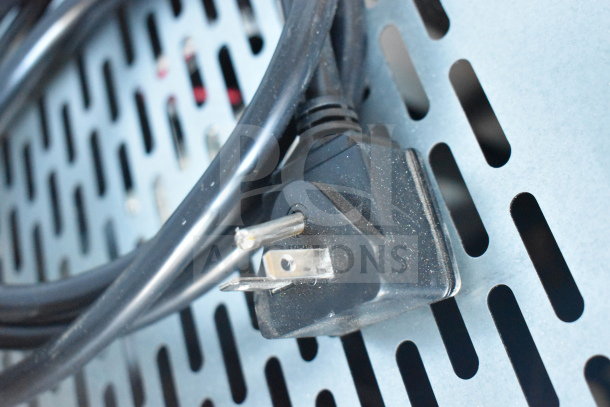 Black power plug and cable for Avantco 193VAC46B refrigerated merchandiser against a perforated metal surface.