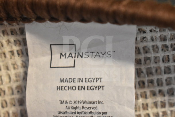 Mainstays Pecan 60"x84" rug label. Shows brand, "Made in Egypt," Mainstays by Walmart. Rug edging and backing visible.