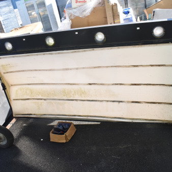 Large outdoor sign with multiple slots for letters, black frame with lights, visible wear and weathering, includes a nearby box possibly containing letters.