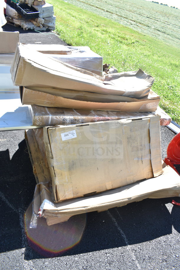 Stack of new, wrapped boxes labeled "Regency," "205," and "6X" containing scratch and dent items, outdoors.