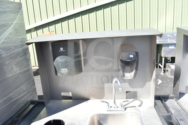 Commercial portable sink on casters, featuring faucet, integrated hand soap and paper towel dispensers. Appears in used condition.