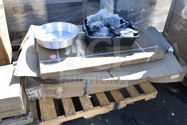Stack of boxed items on a wooden pallet, including a stainless steel wok cover and a paper towel dispenser with a trash can. Items labeled "Enclosed Table Cabinet, 60DETM 300D." Some boxes have minor wear and visible labels.