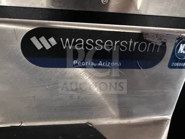 Wasserstrom 48" stainless steel work table, 3-sided backsplash, pristine condition, NSF certified, label reads "Peoria, Arizona."