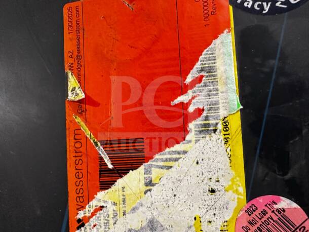 Label on Wasserstrom commercial work table featuring contact info and barcode, partially damaged.