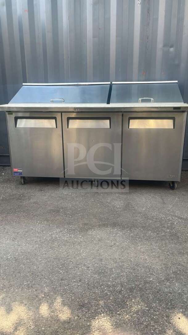 Turbo Air MST-72-30-N 72" stainless steel refrigerated prep table with three doors, mega top, on rolling casters.