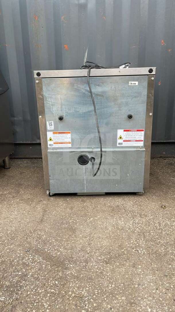 True TUC-27-HC undercounter refrigerator rear view, features visible safety labels, metal finish, power cord attached.