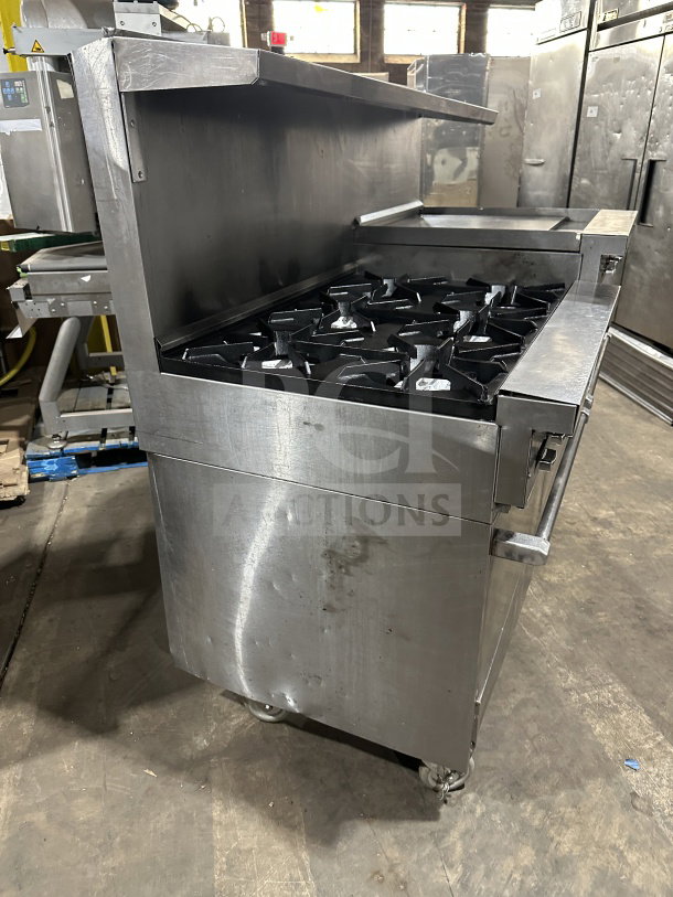 Commercial stainless steel 6-burner gas range with grille, 2 ovens, on casters. Good condition, some surface marks.