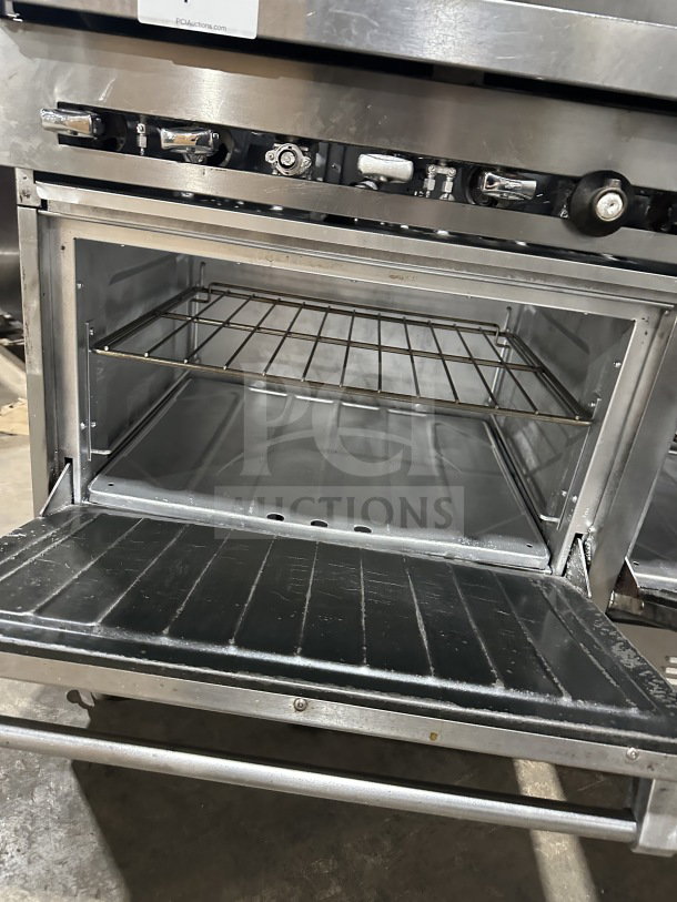 Stainless steel gas-powered 6-burner grill with two standard ovens on casters. Features durable build and modern design.