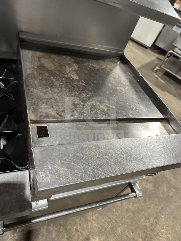 Commercial stainless steel gas-powered 6-burner and grille with two standard ovens, on casters. Visible wear on surface.