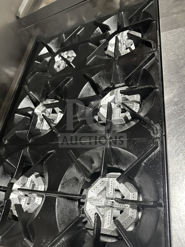 Commercial stainless steel gas-powered 6-burner griddle with 2 standard ovens, on casters, in good condition.