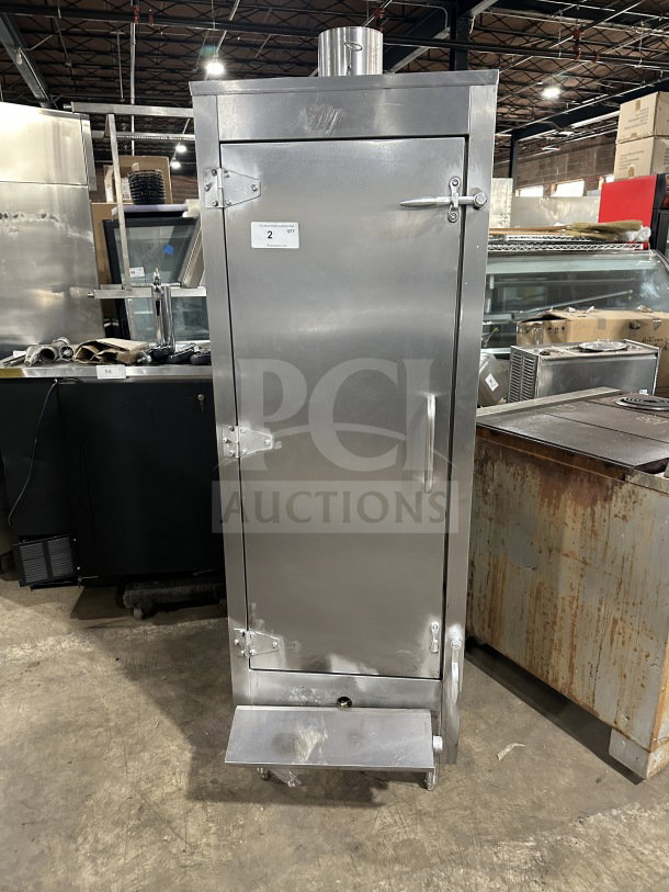 Commercial stainless steel smoker oven with galvanized interior, on legs. Features a front handle and secured door clasps. Item tag: "2 Qty".