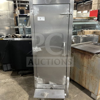 Commercial stainless steel smoker oven with galvanized interior, on legs. Features a front handle and secured door clasps. Item tag: "2 Qty".