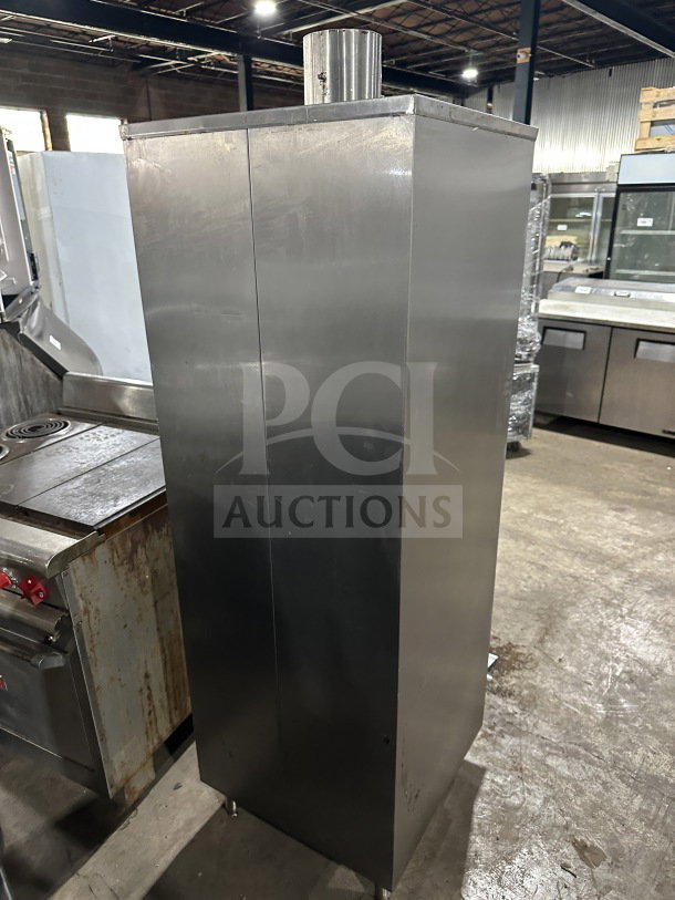 Commercial stainless steel smoker oven with galvanized interior on legs. Features dual doors and a chimney. Good condition.