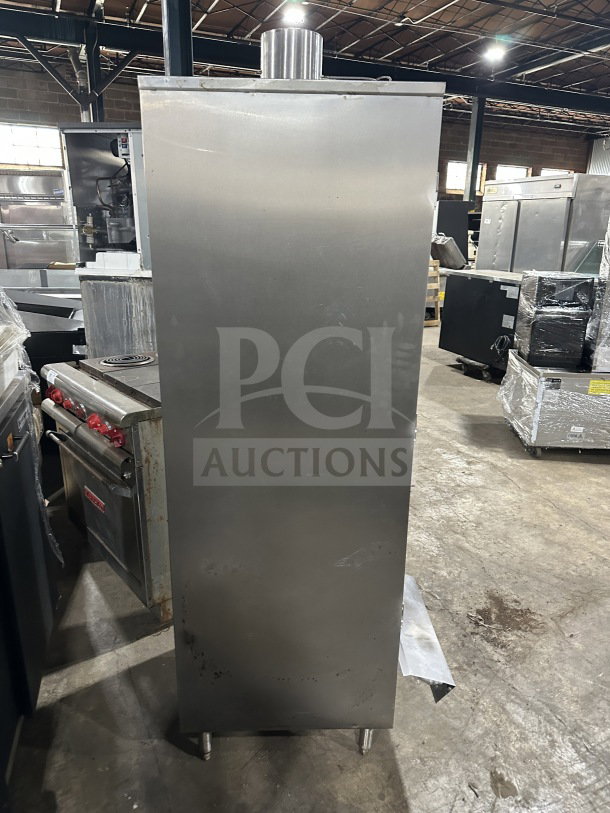 Stainless steel commercial smoker oven with galvanized interior on legs, standing in a warehouse, good condition.