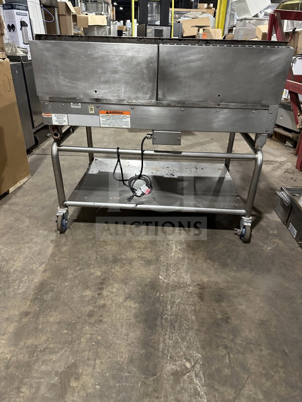 Commercial stainless steel gas griddle with thermostatic control, integrated divider, stand on casters, visible warning labels.