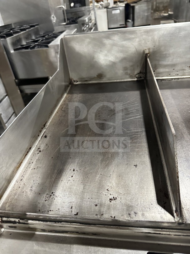 Commercial stainless steel gas griddle with thermostatic control, integrated divider, and stand on casters. Used condition.