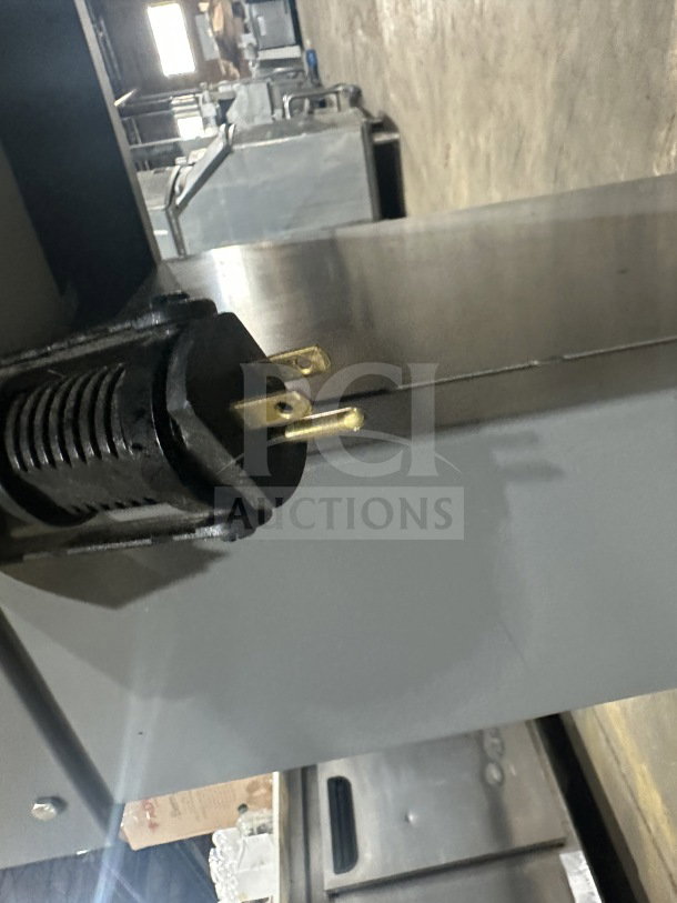 Beseler electric shrink wrap system TD-16-10, 220V 1 Phase, on casters, close-up of power plug in warehouse setting.